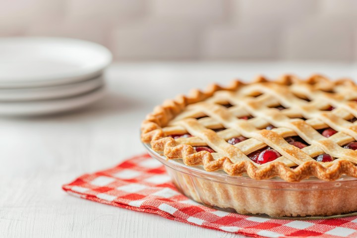 Freshly baked cherry pie with golden lattice crust on a red gingham cloth
