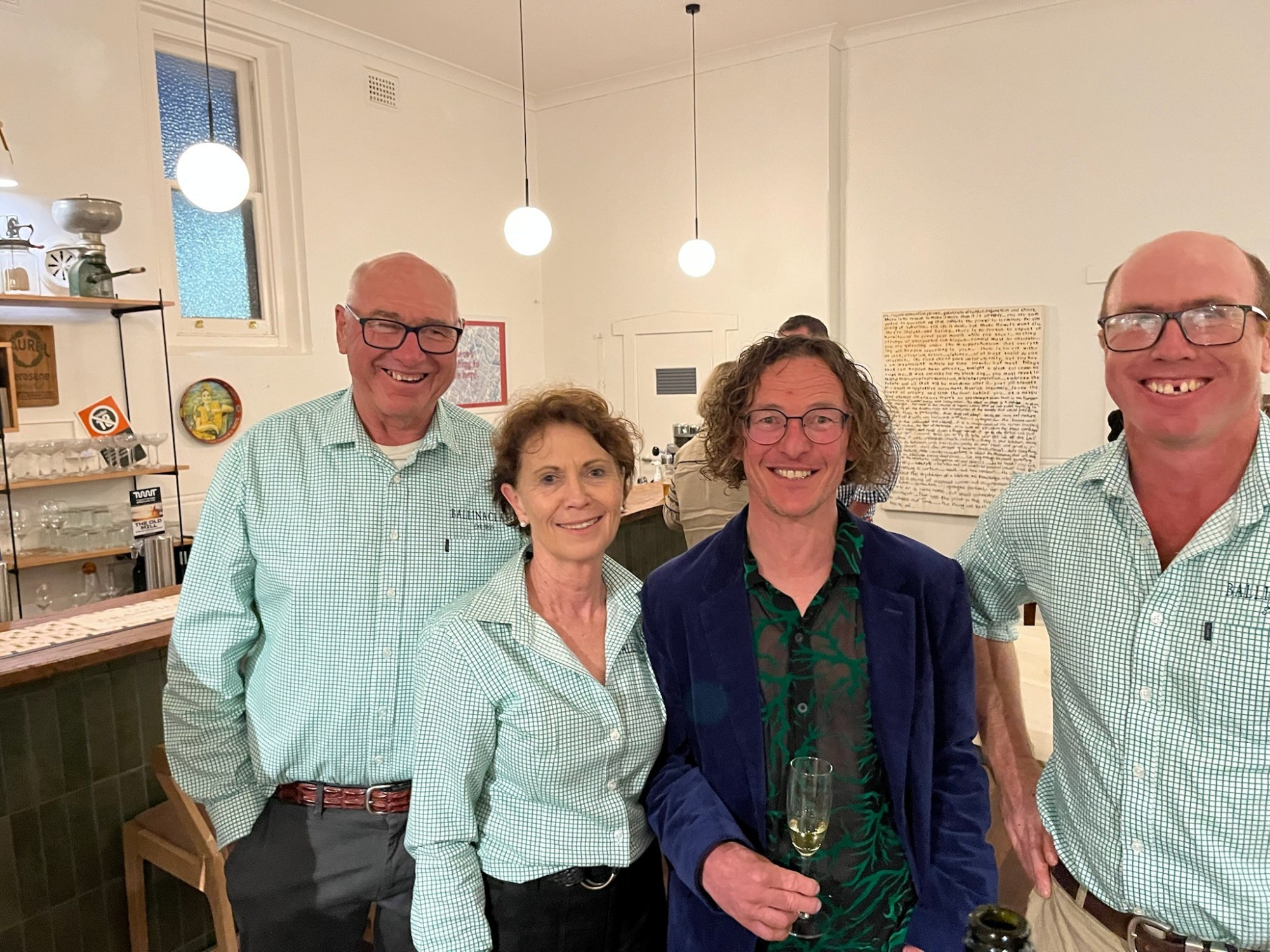 Pete, Cath & Ned Mullany from Ballinaclash with with their wine maker, Chris Derrez Four people smiling indoors, three wearing light green shirts, one in a dark jacket, under hanging lights.